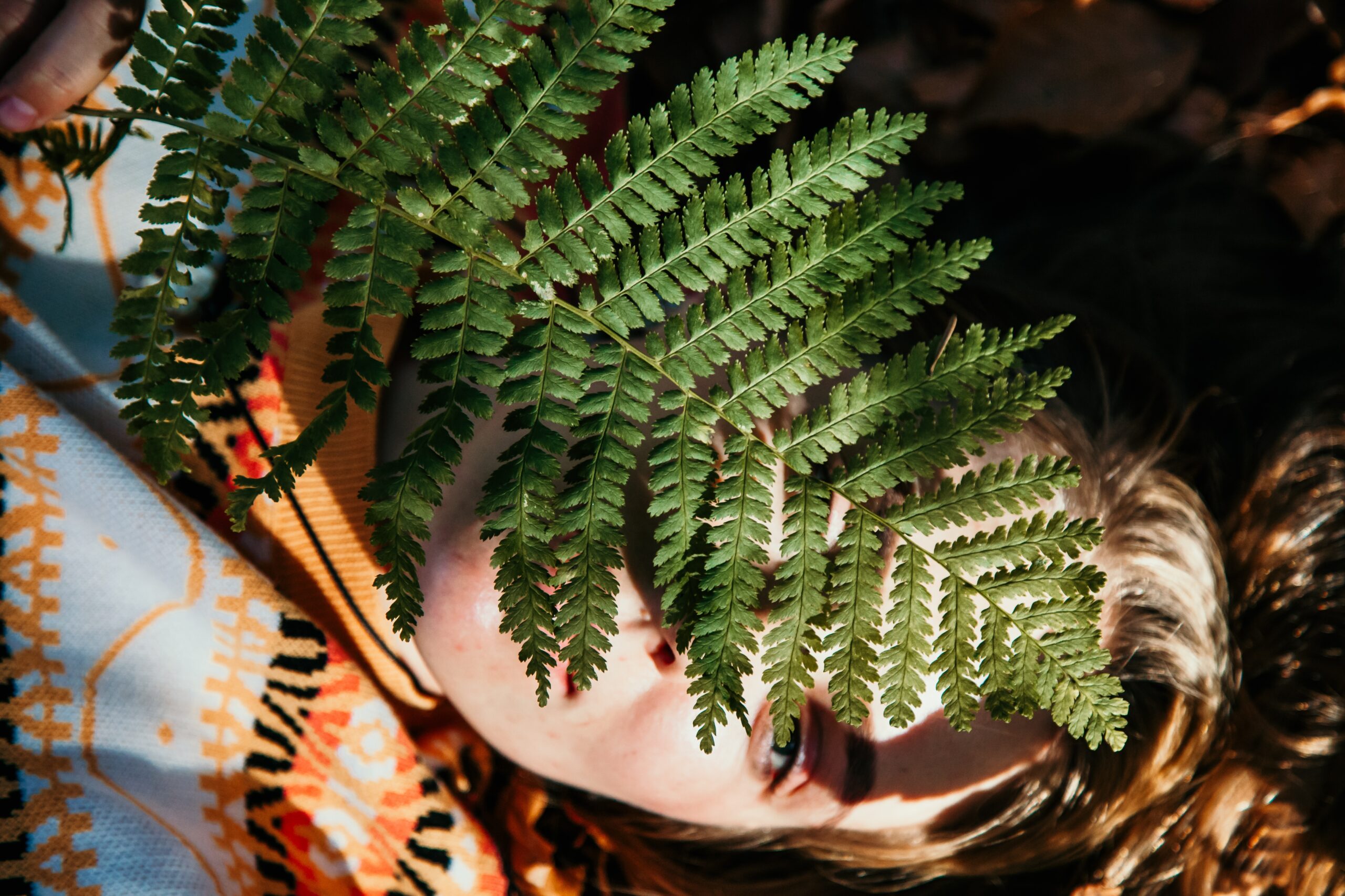 Vrouw in rust met varen boven haar hoofd, symbool voor harmonie tussen natuur en innerlijke vrede.