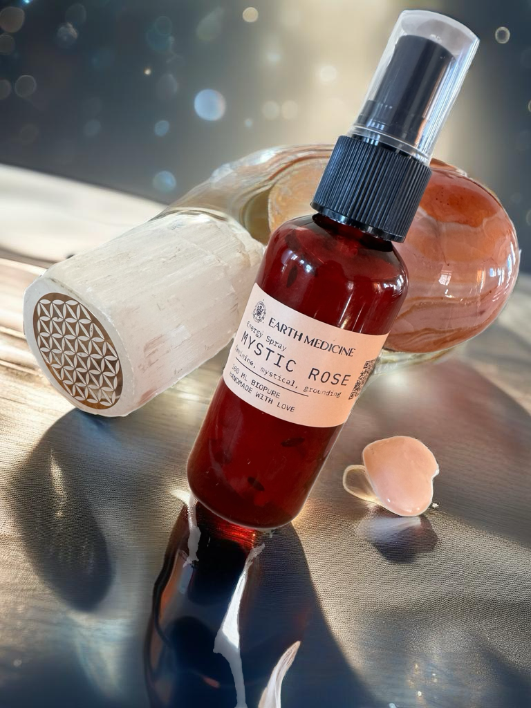 Een prachtige Energy Spray-fles op een glanzend oppervlak, vergezeld door een seleniet staaf, een rozenkwarts hart en een oranje kristallen bol. De compositie straalt harmonie, zuiverheid en energetische balans uit, perfect voor rituelen en dagelijkse verfrissing.