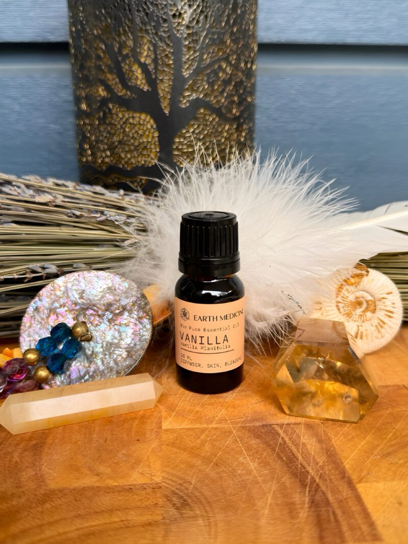 Flesje Vanille essentiële olie op een houten plank met citrienkristal, veren en lavendel op de achtergrond.