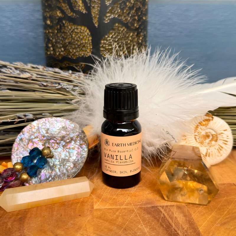 Flesje Vanille essentiële olie op een houten plank met citrienkristal, veren en lavendel op de achtergrond.