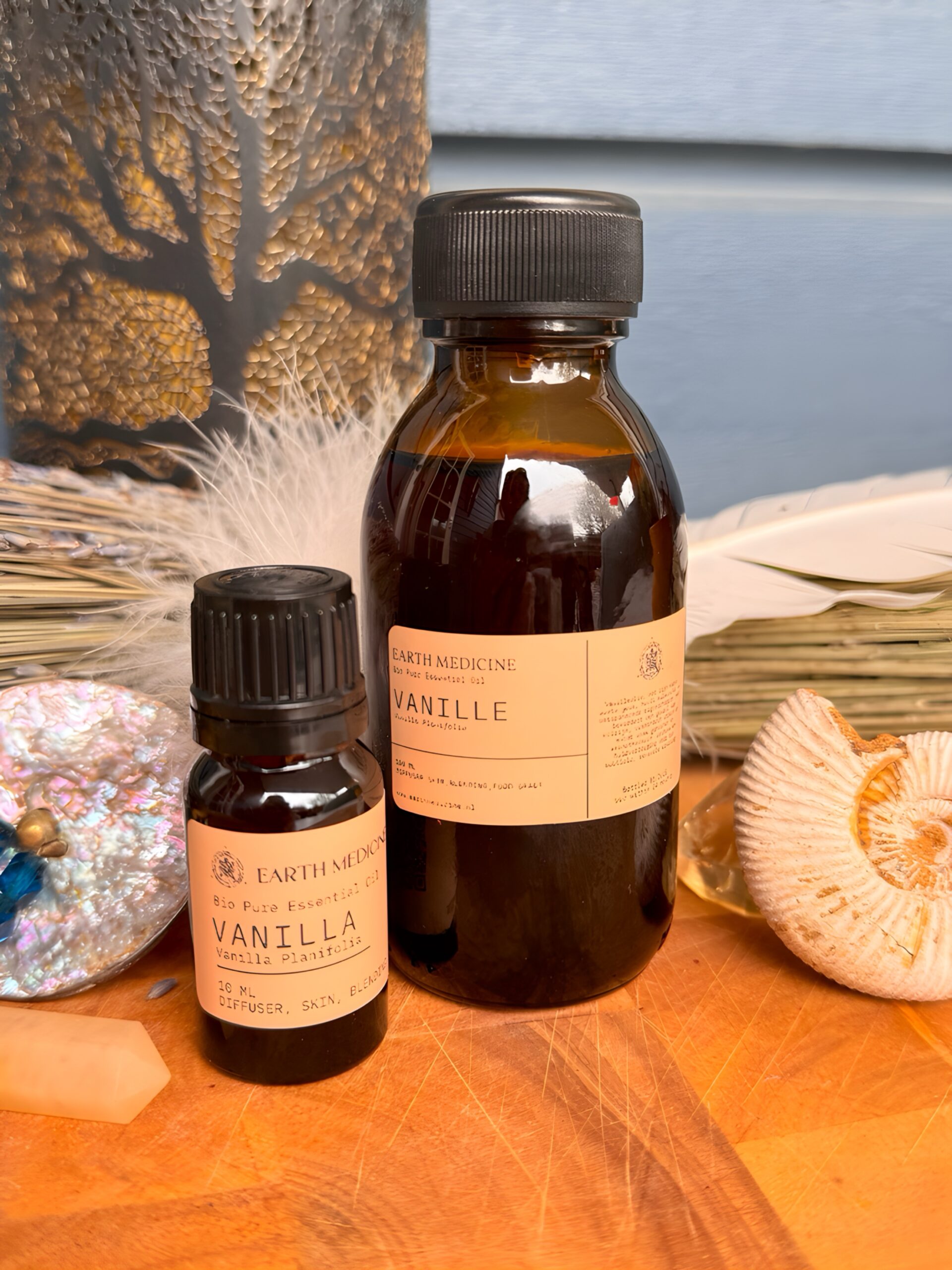 Twee flesjes Vanille essentiële olie van 100 ml en 10 ml in een warm, natuurlijk Earth Medicine sfeerbeeld.