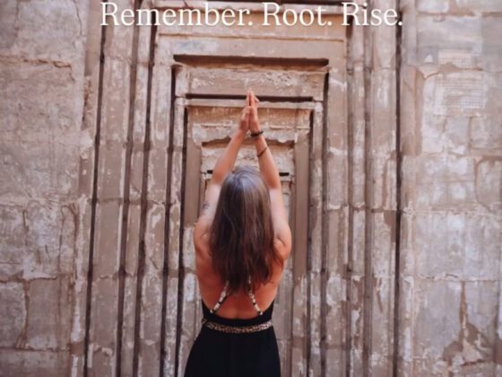 Vrouw met opgestoken armen staat in een tempelopening in Luxor, Egypte, in een rituele houding van overgave en verbinding, met de tekst “Remember. Root. Rise.” erboven.